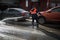 A worker washes the street in places where cars are parked