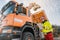 Worker watching a lorry with gripper unloading biomass