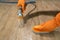 Worker wearing orange rubber gloves is scrub cleaning dirty filthy patio floor