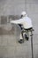 Worker wearing a protective gear cleaning a stone faceade in rope access