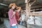 a worker wears a hat with a thumbs up and feeds the cows using a bucket with copyspace