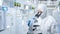 Worker wears medical protective suit or white coverall suit look through microscope in laboratory