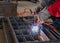 Worker welding steel grill pipe cap in factory