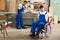 Worker in wheelchair in a carpenter\'s workshop with his colleagu