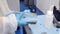 Worker in white protective suit and blue protective gloves cleaning metal part