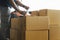 Worker writing on clipboard his doing inventory management product boxes on pallet. Checking stock, Shipment, packaging.