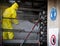 Worker in a yellow plastic overall is busy with high pressure cleaning a heat exchanger