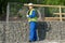 Worker in a yellow vest and a white helmet, carries a roll of wire on his shoulder