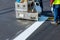 Workers apply a road marking to the stripe with white paint and sprinkle the stripes with a reflective powder on the