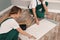 Workers applying glue onto wall paper sheet on floor