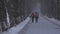 Workers in black orange jumpsuits walk along park road