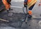 The workers` brigade clears a part of the asphalt with shovels in road construction