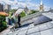 Workers building solar panel system on roof of house. Installers carrying photovoltaic solar module