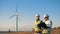 Workers check windmills in a field, walking. Renewable electririty, green energy concept.