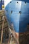 Workers cleaning impurities and removing paint with a pressure sandblasting from the hull of a merchant ship