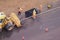 Workers fill a hole in the sidewalk laying new asphalt from the bucket of a bulldozer