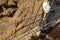 Workers hands using steel wire and pincers to secure rebar before concrete is poured over it