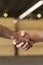 Workers handshake at shed factory with wood pile at background