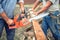 Workers, handymen cutting timber wood using mechanical chainsaw.