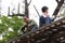 Workers install roof tiles