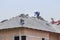 Workers installing concrete tiles on the roof while roofing house