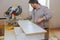 Workers installing laminate and measuring laminated white shelves before cutting.