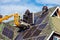 Workers installing solar panels on private home hexagonal roof felt on sunny day  blue sky.