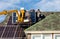 Workers installing solar panels on private home hexagonal roof felt on sunny day  blue sky.