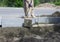 Workers level the cement with a shovel near the installed concrete curbs.