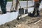 Workers level the cement with a shovel near the installed concrete curbs.