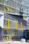 Workers on a lift platform cleaning the windows of a building with a pedestrian walking on the street