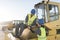 Workers looking phone in bulldozer shovel roll site