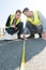 Workers measuring along tarmac surface