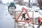 Workers in the municipal utilities repair a broken pipe in the winter. Excavated pit, fenced and with warning signs