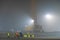 Workers on the night shift prepare a reinforcing frame for pouring it with concrete. Foundation construction. Night fog