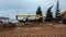 Workers plain ground near building machines under cloudy sky