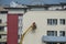 Workers plasterers on a crane repair the facade of a old panel concrete house