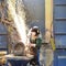 Workers in protective equipment in a foundry work on a casting with a grinding machine at the workplace