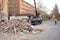 Workers of public services put construction waste from the demolition of old stalls in a truck with a crane in the alley