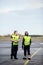 Workers In Reflective Jackets Standing On Airport Runway