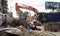 Workers stand near an excavator