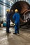 Workers supervising the manufacture of a metallic cylinder