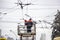 Workers on the tower repair the contact mains network for trolley buses