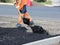 Workers in uniform throw shovels of asphalt on the road.