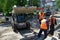 Workers using a mini backhoe loader establish a curb at the crossroads of city streets. May 29, 2020, Russia, Magnitogorsk