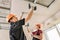 Workers are using screws and a screwdriver to attach plasterboard to the ceiling