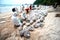 Workers and volunteers are shoveling sand with crude oil contaminated on the beach in a large plastic bag.