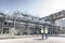 Workers walking past process tanks in oil blending factory.