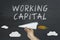 Working Capital concept with flying paper plane on blackboard