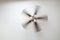 A working ceiling fan on a white ceiling, close up with blurred fan blades, three lamps, daytime.